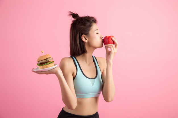 femme-asiatique-choix-entre-hamburger-pomme-rouge-rose_1150-13180
